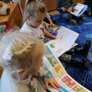 Dzieci siedzą na dywanie i oglądają książki
