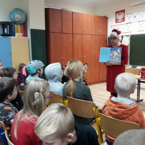 Bibliotekarka goszcząca w przedszkolu pokazuje dzieciom ksiażkę