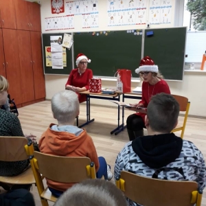 Bibliotekarka w czapce Świętego Mikołaja czyta dzieciom bajkę